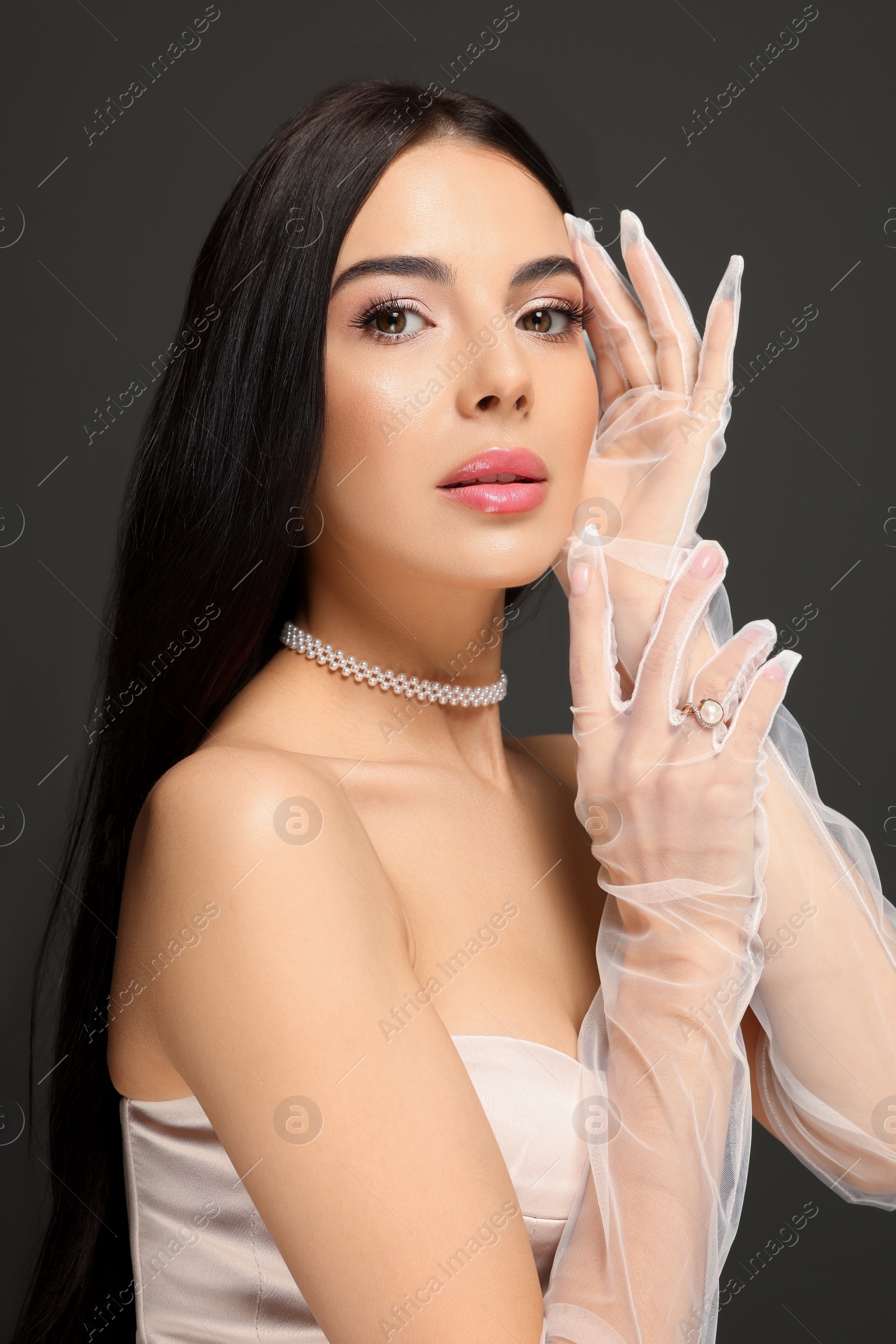 Photo of Portrait of beautiful young woman in evening gloves on black background