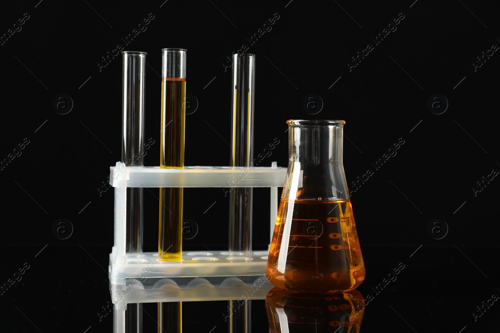 Photo of Laboratory glassware with different types of oil on black background