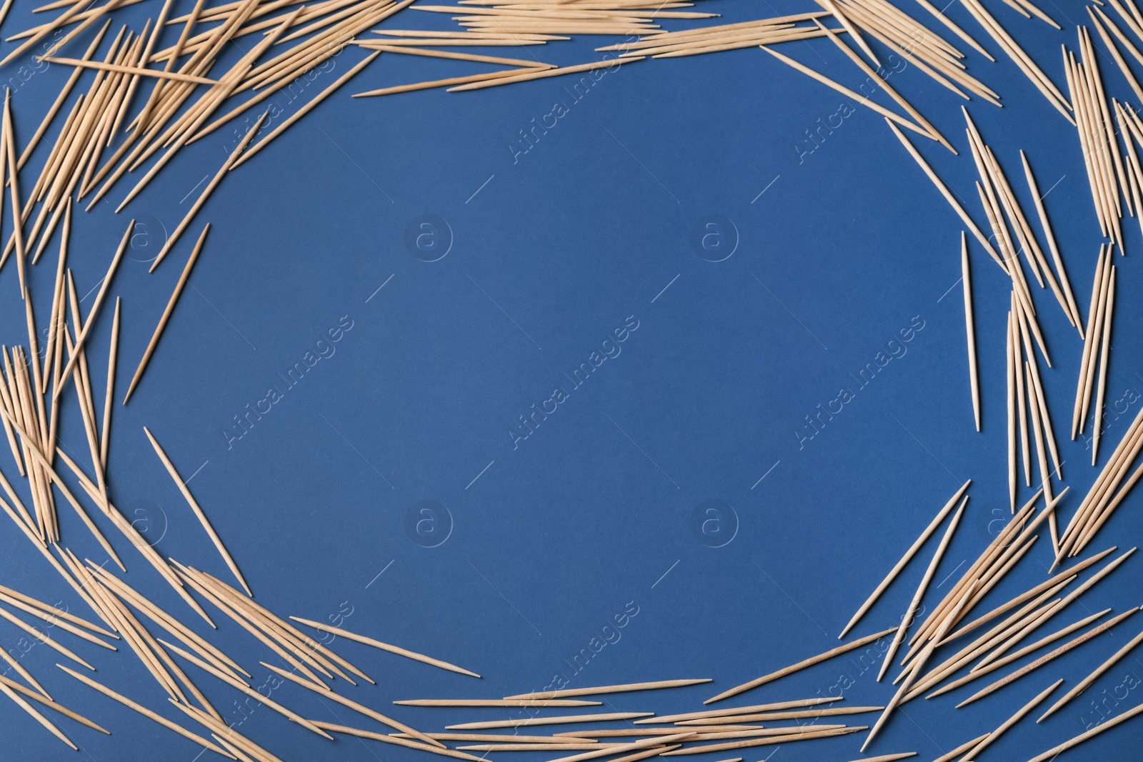 Photo of Frame of wooden toothpicks on blue background, flat lay. Space for text