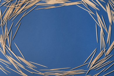 Frame of wooden toothpicks on blue background, flat lay. Space for text