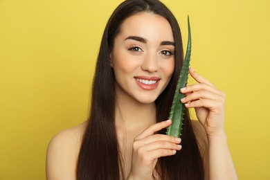 Photo of Young woman with aloe vera leaf on yellow background