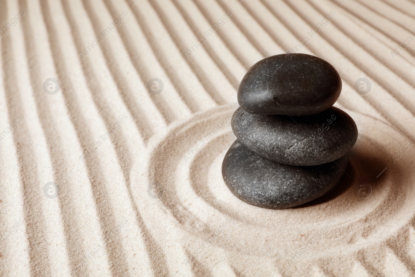 Photo of Stacked zen garden stones on sand with pattern, space for text. Meditation and harmony