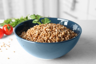 Bowl of buckwheat porridge with parsley on white table