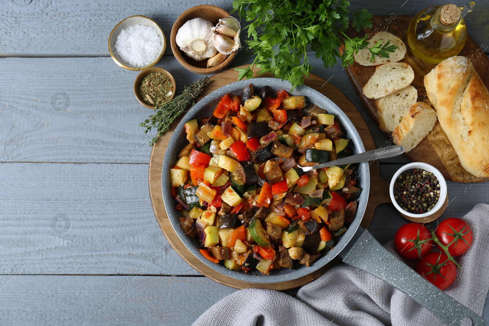 Photo of Delicious ratatouille and ingredients on grey wooden table, flat lay. Space for text