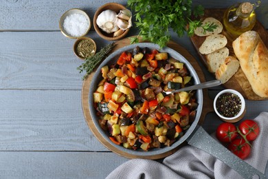Delicious ratatouille and ingredients on grey wooden table, flat lay. Space for text