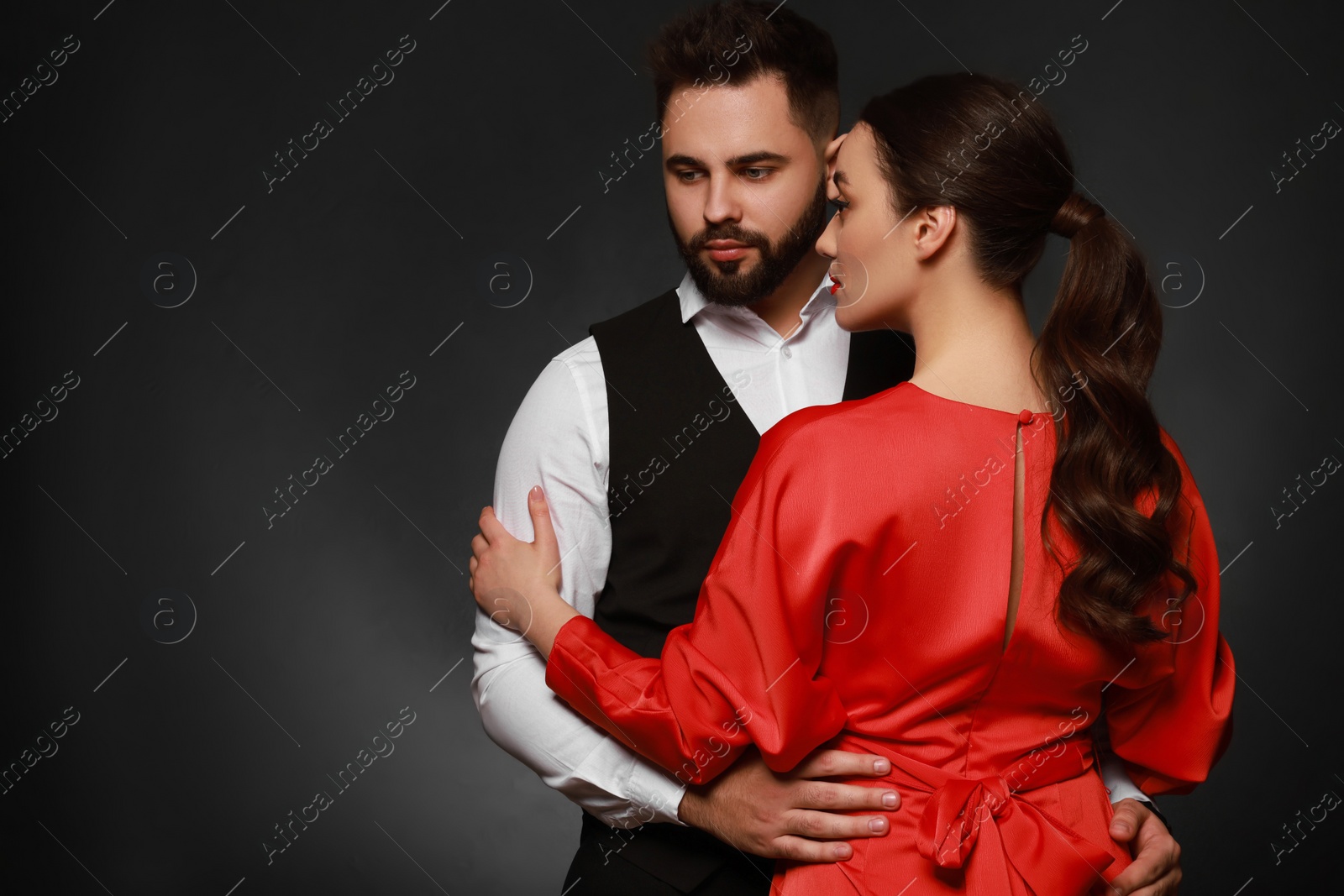 Photo of Handsome bearded man with sexy lady on dark background. Space for text