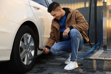 Photo of Handsome man inflating tire at car service