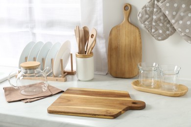 Wooden cutting boards, other cooking utensils and dishware on white countertop in kitchen