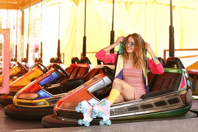 Photo of Happy girl with retro roller skates sitting in entertainment park