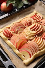 Photo of Baking tray with uncooked apple galette on wooden table, closeup