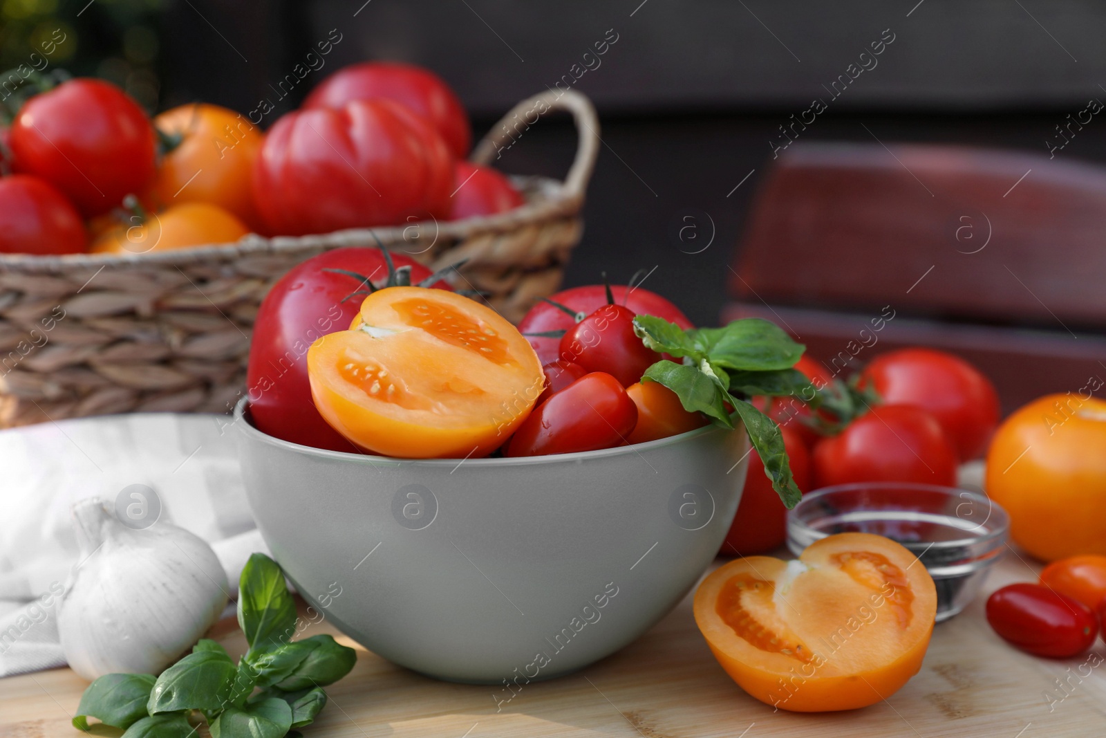 Photo of Different sorts of tomatoes with basil on wooden table