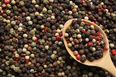 Photo of Closeup of wooden spoon with mixed peppercorns, top view