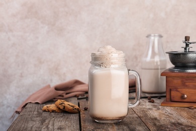 Photo of Mason jar with delicious milk shake on wooden table