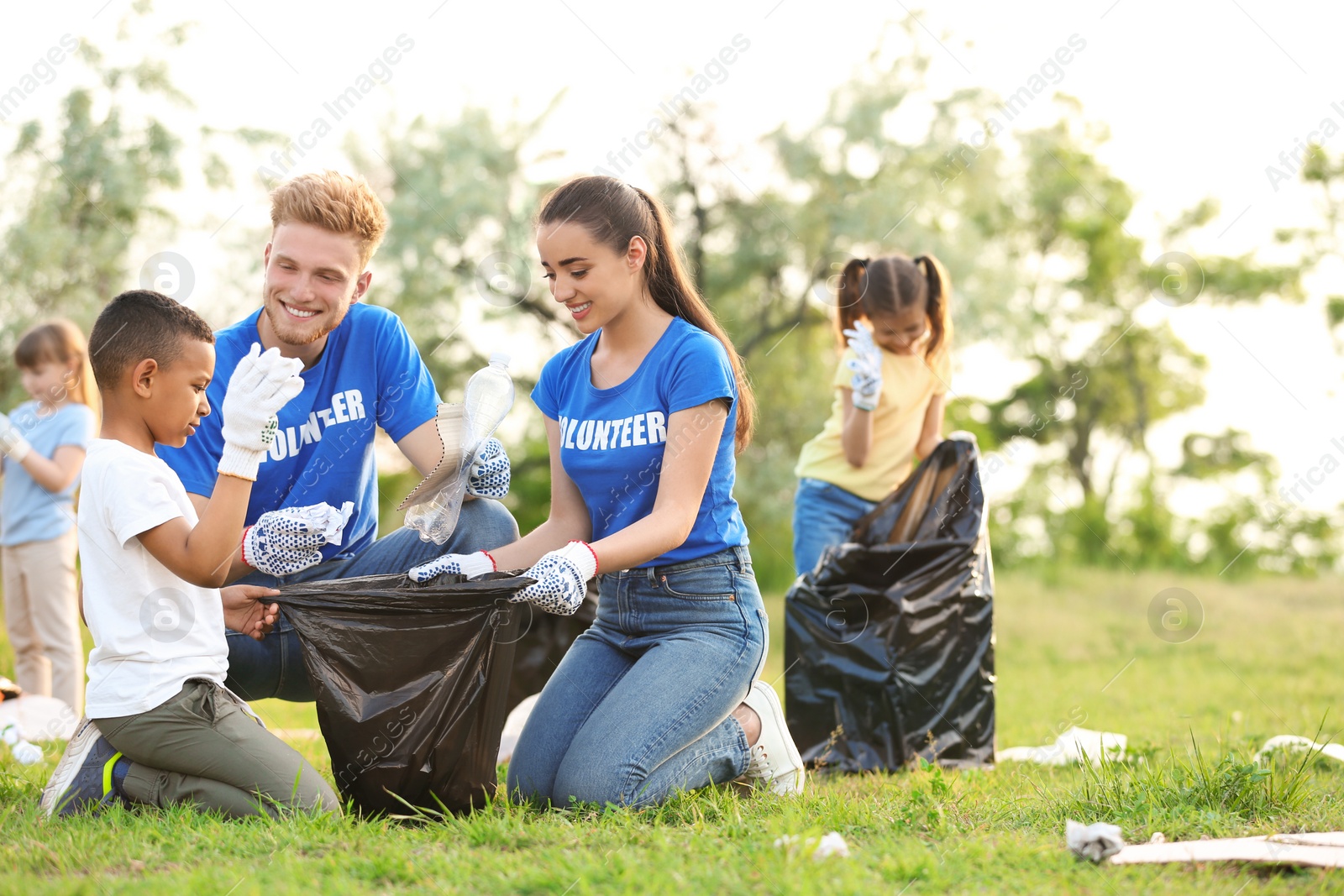 Photo of Little African-American boy collecting trash with volunteers in park