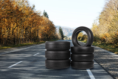 Image of Stacks of car tires on asphalt highway outdoors