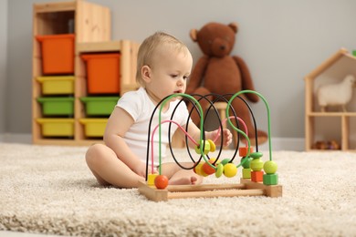 Children toys. Cute little boy playing with bead maze on rug at home