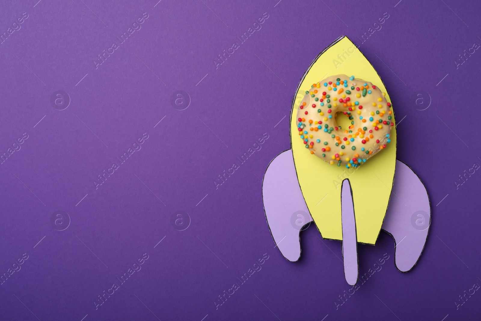 Photo of Rocket made with donut and paper on purple background, top view. Space for text