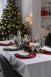 Christmas table setting with festive decor and dishware in room