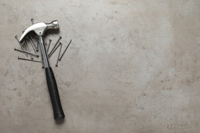 New hammer and metal nails on grey table, flat lay. Space for text