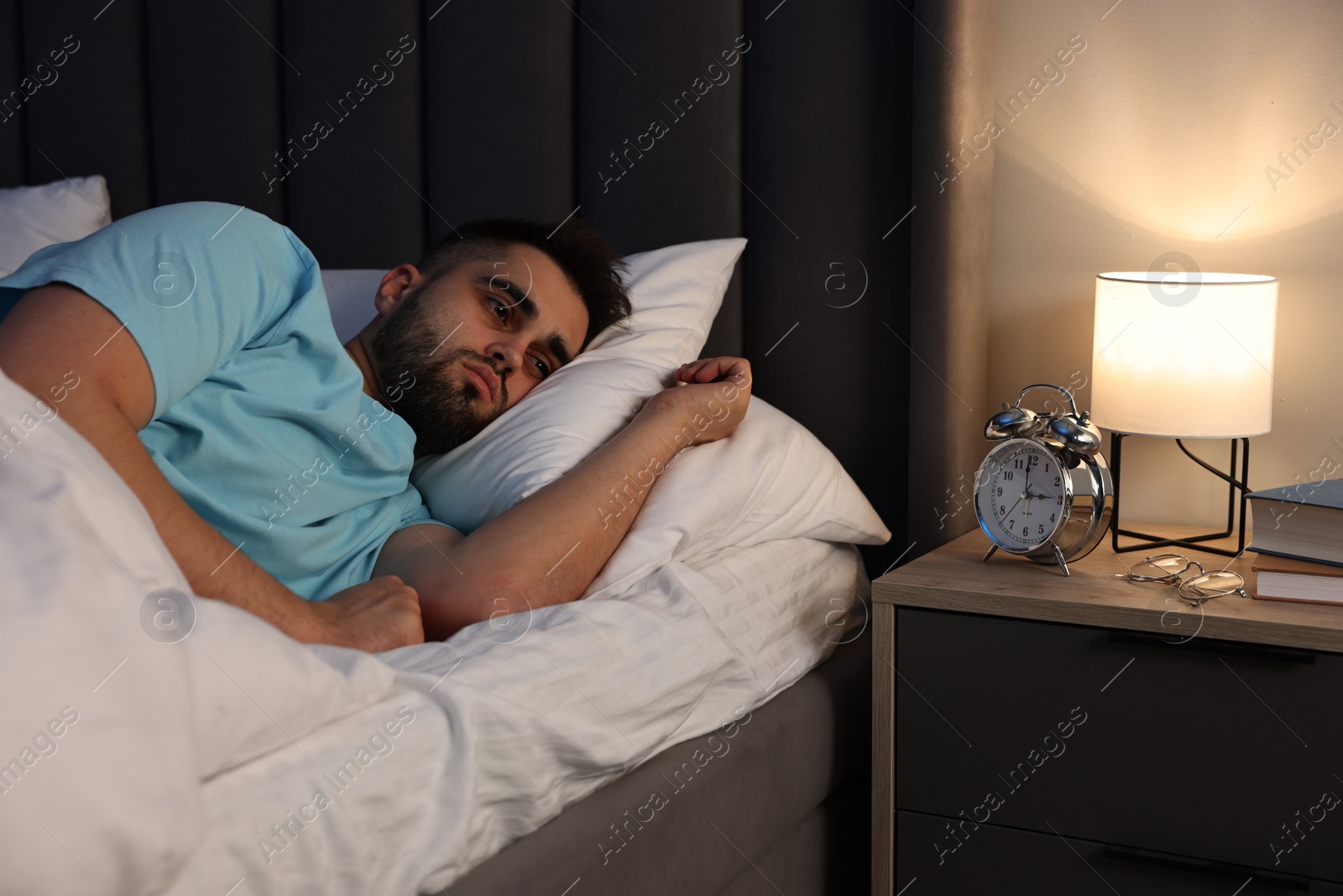 Photo of Frustrated man suffering from insomnia in bed