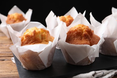 Photo of Delicious sweet muffins on wooden table against dark background, closeup