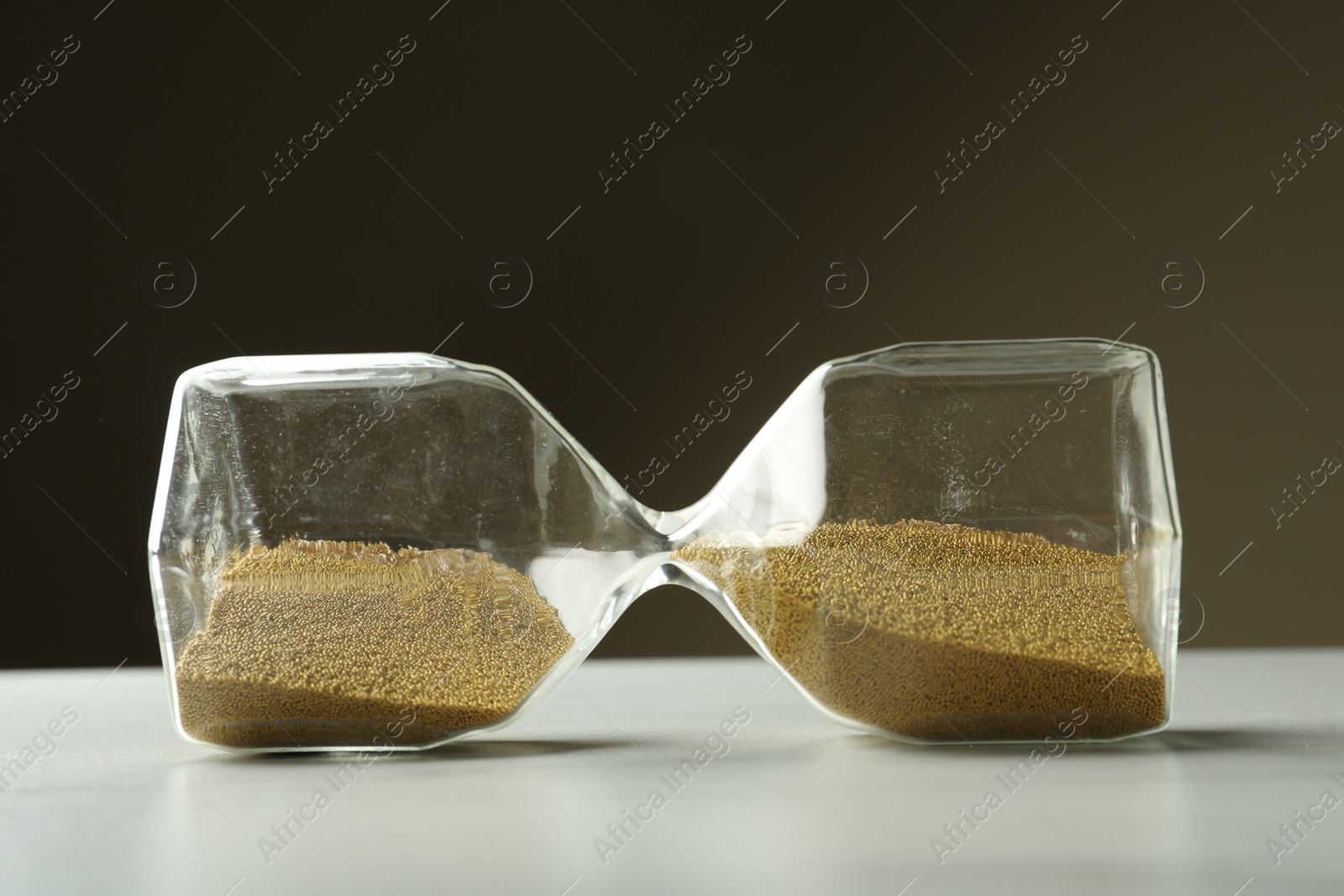 Photo of Hourglass with sand on white table. Menopause concept
