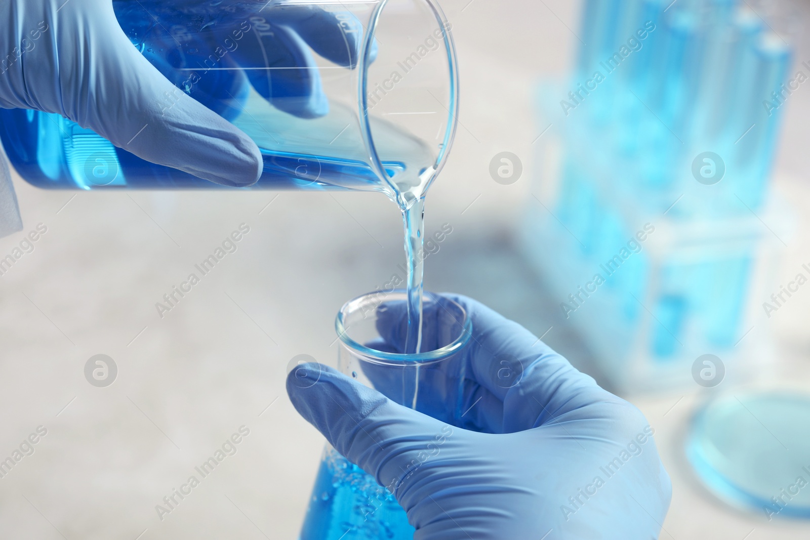 Photo of Scientist working with beakers at grey table, closeup