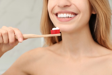 Photo of Woman holding brush with toothpaste indoors, closeup