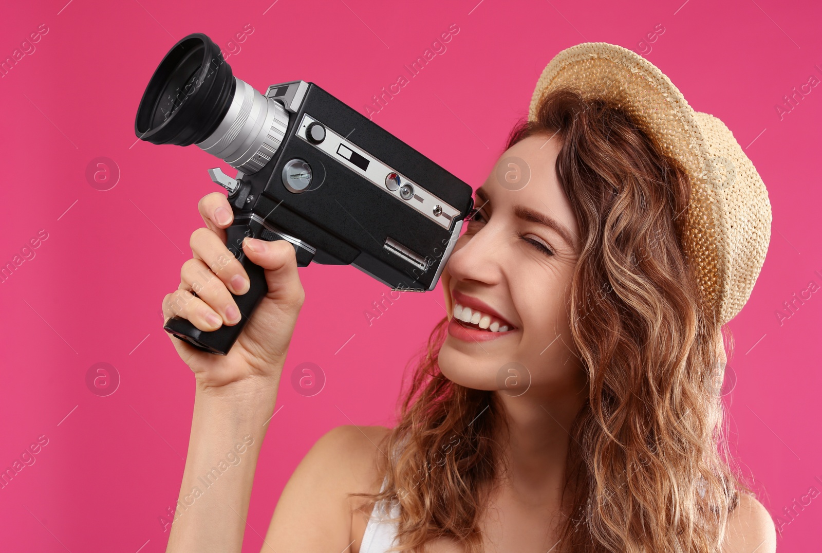 Photo of Beautiful young woman using vintage video camera on crimson background
