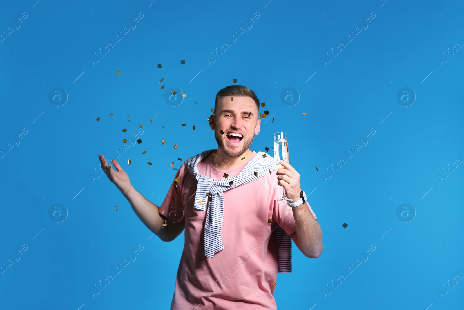 Photo of Portrait of happy man with champagne in glass and confetti on color background