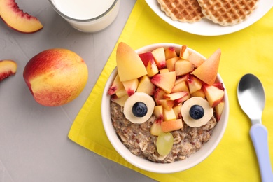 Photo of Tasty porridge served with fruits, milk and waffles on grey table, flat lay. Creative idea for kids breakfast