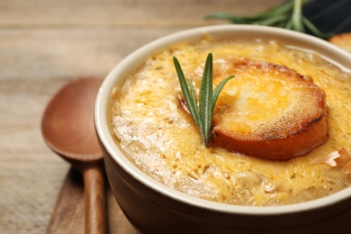 Tasty homemade french onion soup on wooden table, closeup