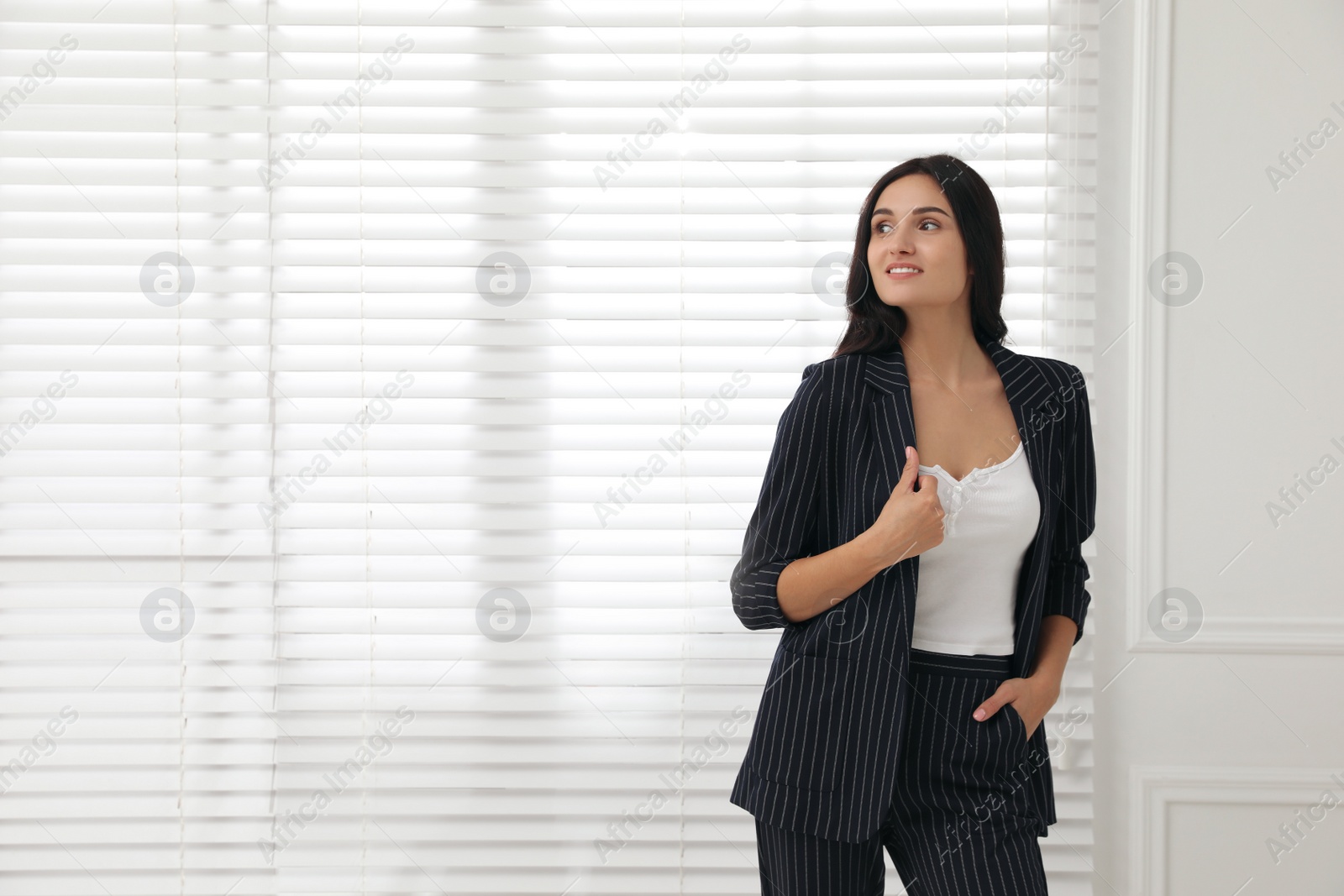 Photo of Beautiful woman in formal suit near window, space for text. Business attire