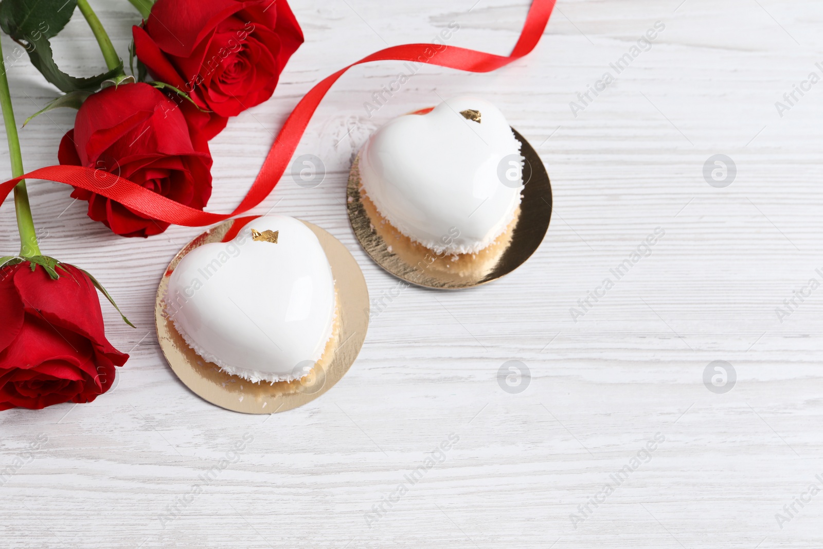 Photo of St. Valentine's Day. Delicious heart shaped cakes and roses on white wooden table, flat lay. Space for text