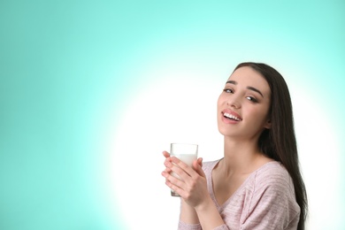 Photo of Beautiful young woman drinking milk on color background