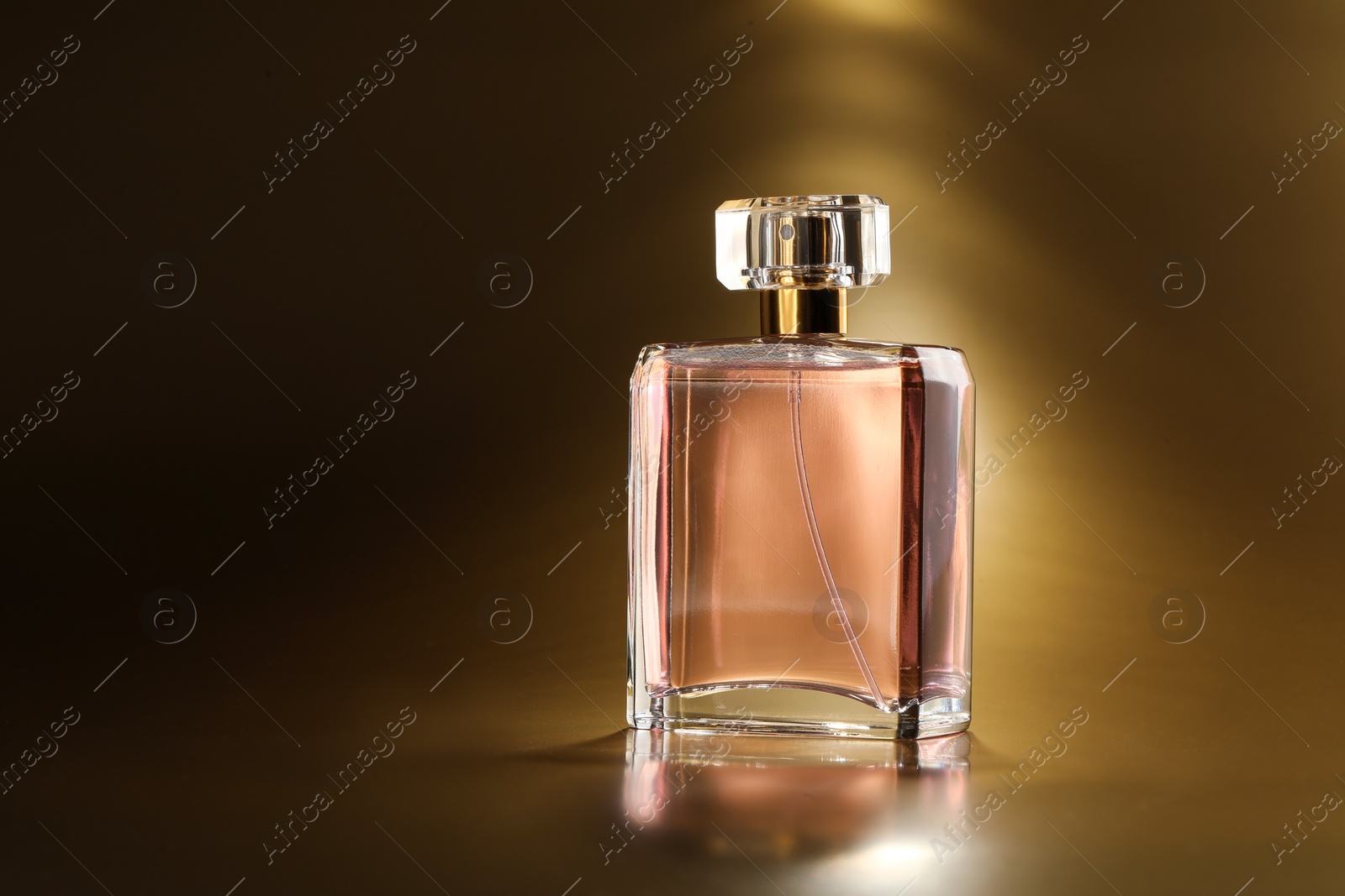 Photo of Luxury women's perfume. Sunlit glass bottle on golden background, space for text