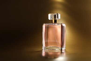 Luxury women's perfume. Sunlit glass bottle on golden background, space for text