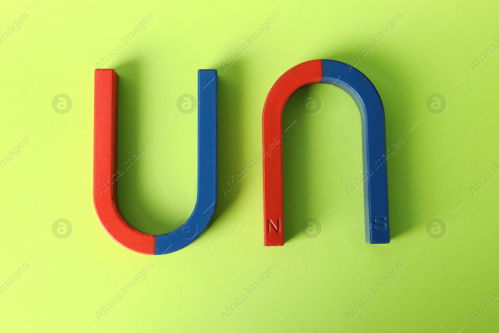 Photo of Red and blue horseshoe magnets on color background, top view