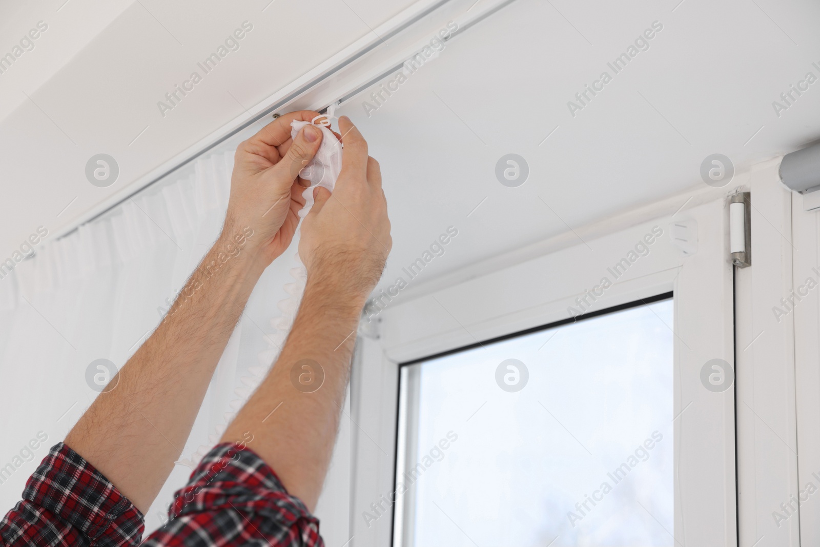 Photo of Worker hanging window curtain indoors, closeup view