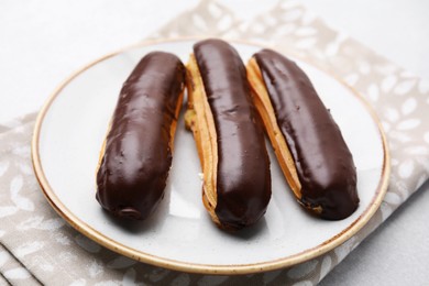 Photo of Delicious eclairs covered with chocolate on grey table, closeup