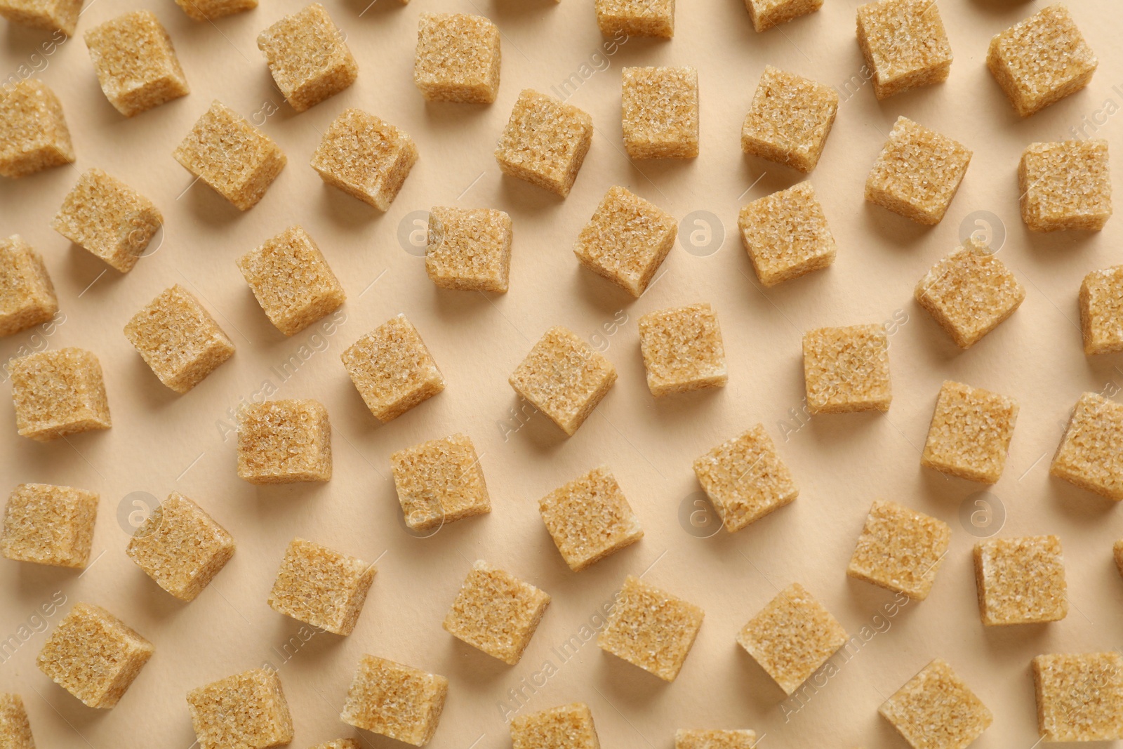 Photo of Brown sugar cubes on beige background, top view