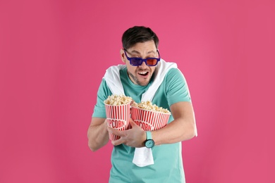 Emotional man with 3D glasses and tasty popcorn on color background