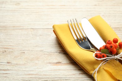 Photo of Closeup view of cutlery with napkin and ashberries on white wooden table, space for text. Thanksgiving Day