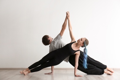 Photo of Young man and woman practicing yoga indoors
