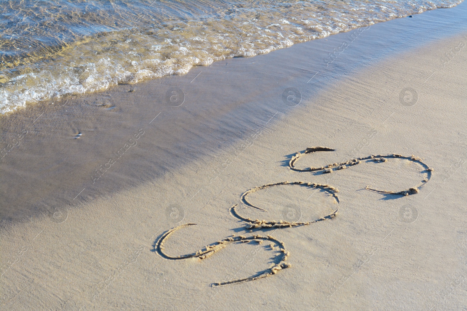 Photo of SOS message written on sand near sea