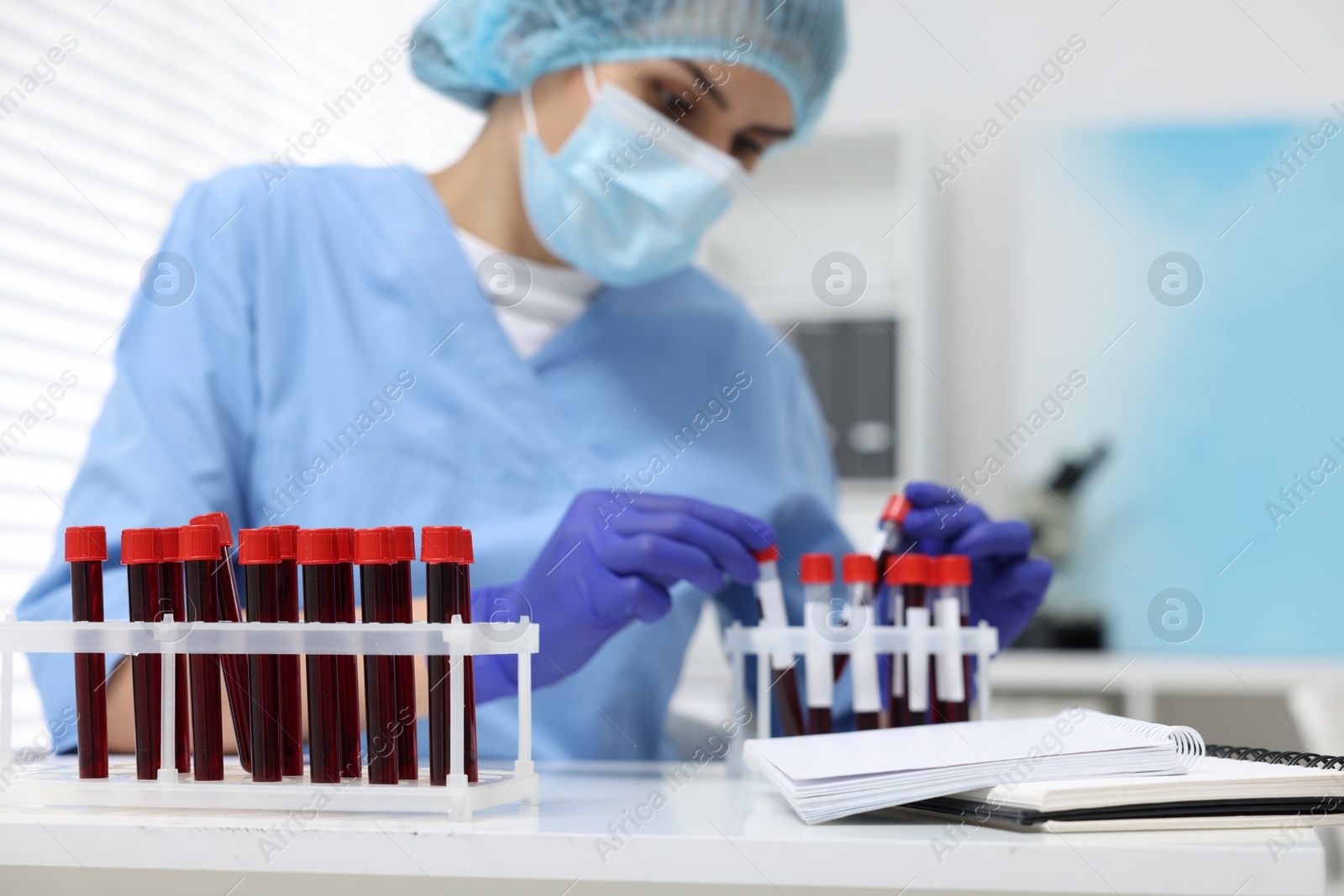 Photo of Laboratory testing. Doctor with blood samples in tubes at white table indoors, selective focus