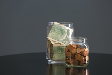 Photo of Donation jars with money on table against grey background