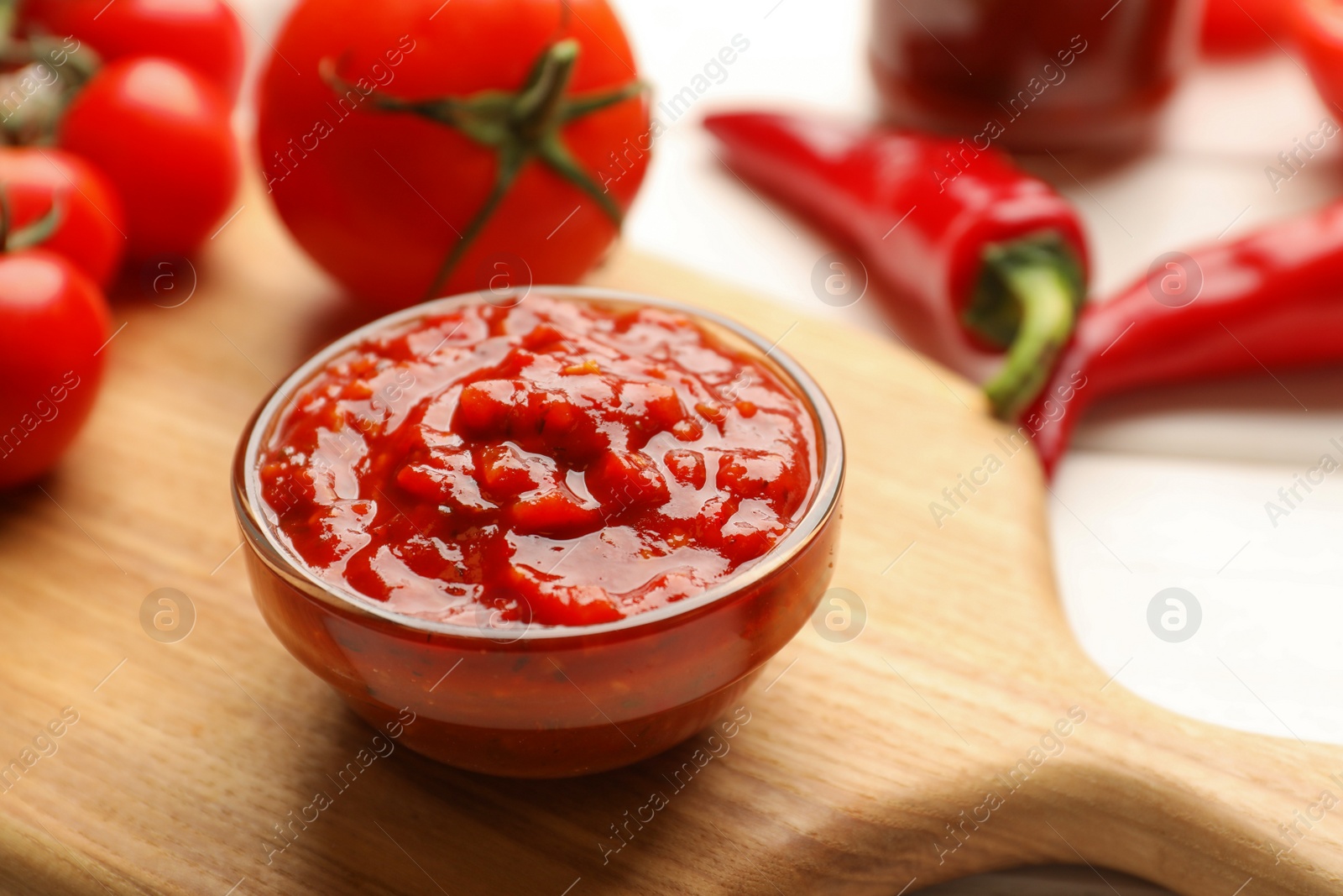 Photo of Delicious adjika sauce in bowl and ingredients on table, closeup