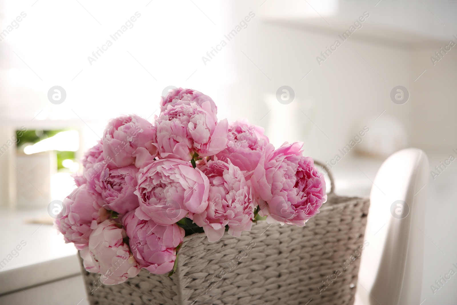 Photo of Basket with beautiful pink peonies in kitchen