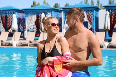 Happy young couple near swimming pool at resort